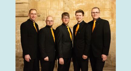 Das Bild zeigt die fünf Mitglieder von Ensemble Felix, alle in schwarzem Anzug mit orange-gelber Krawatte, in der Nikolaikirche Dippoldiswalde.